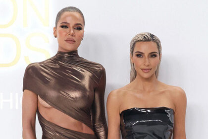 Khloe Kardashian and Kim Kardashian posing at an event.