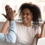 Young black colleagues high-fiving each other at work