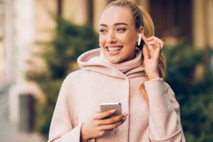 Smiling white woman holding iPhone with Airpods in ear