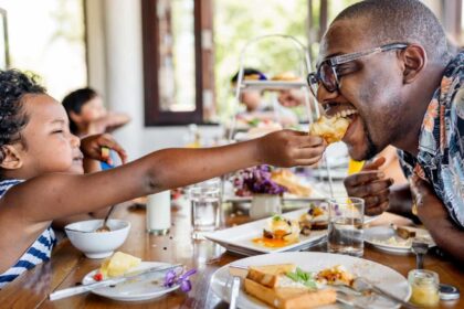 A Black father and daughter having breakfast at hotel restaurant