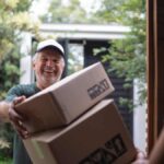 Middle-aged white male courier delivering boxes to young black lady