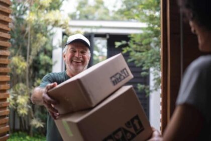 Middle-aged white male courier delivering boxes to young black lady