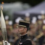 The Olympic torch lights up France's Bastille Day military parade