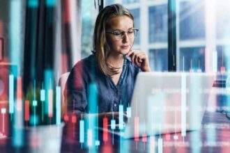 Young woman working at modern office. Technical price graph and indicator, red and green candlestick chart and stock trading computer screen background.