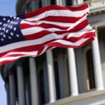 The flag of the United States of America flying in front of the Capitol building