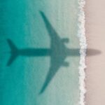 Aerial shot showing an aircraft shadow flying over an idyllic beach