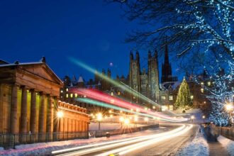 Light trails from traffic moving down The Mound in central Edinburgh, Scotland during December