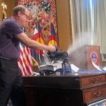 Gov. Jared Polis cuts through executive orders — wielding a circular saw on his desk